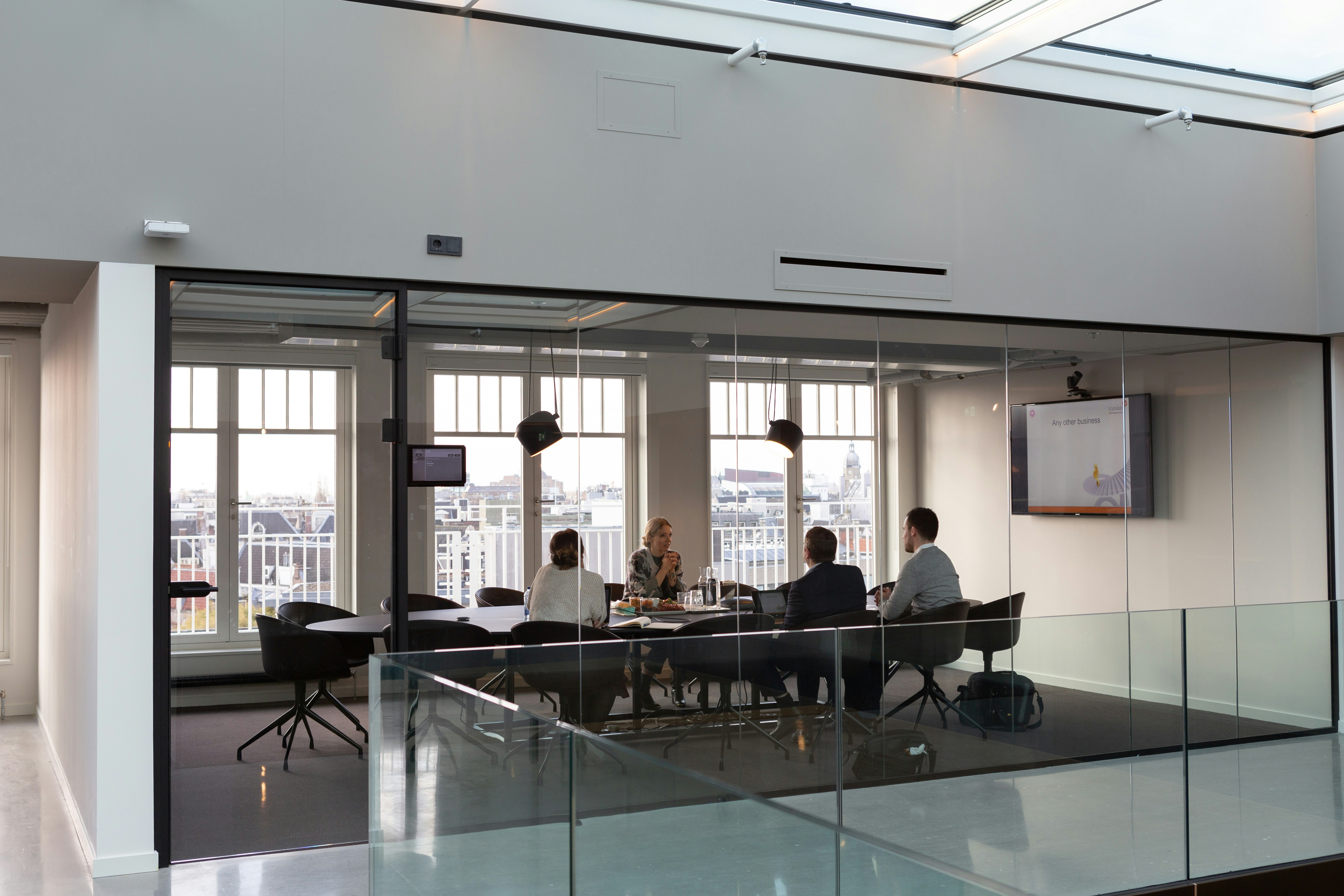 Business consultant presenting project estimate to clients in modern conference room with glass walls