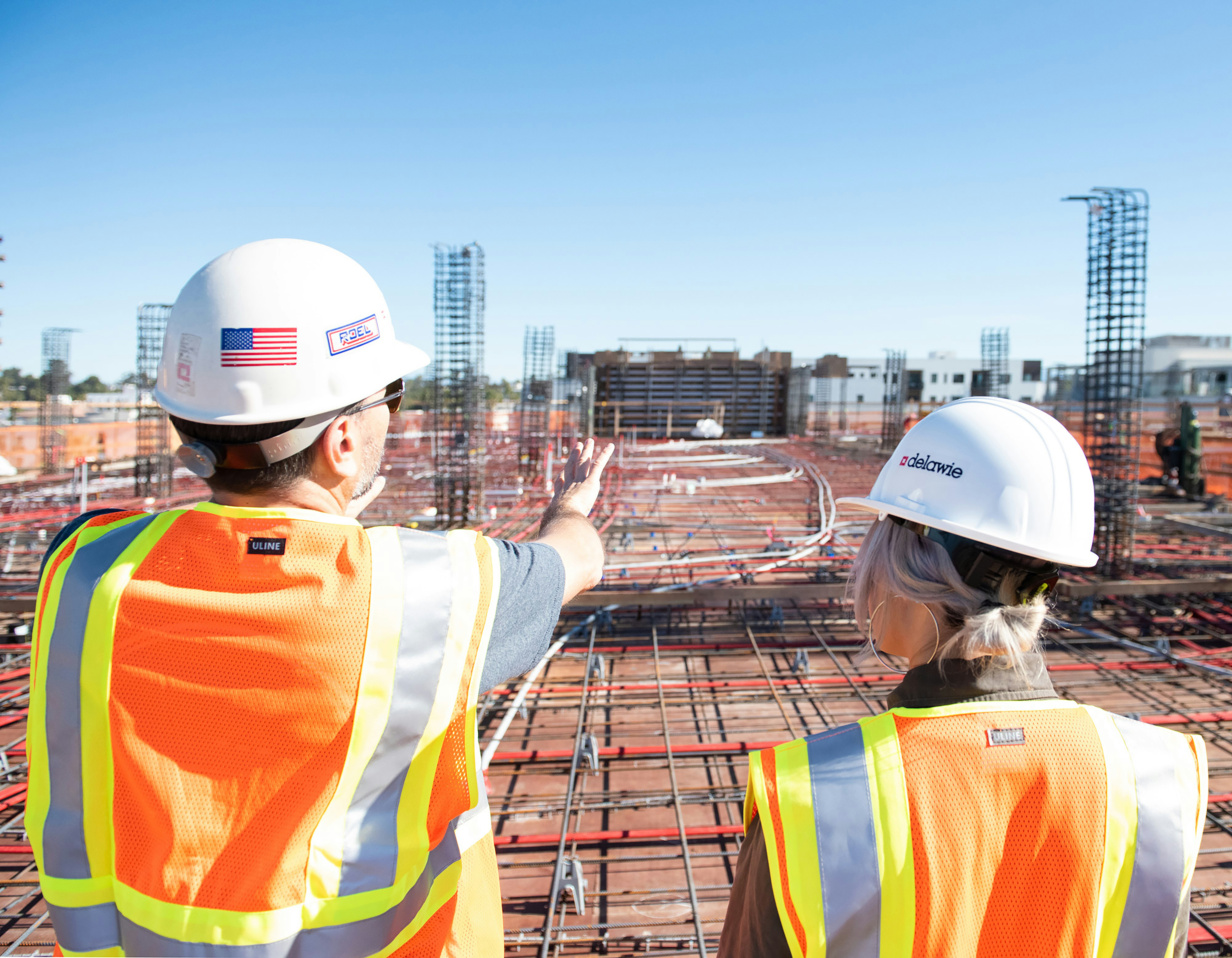 Construction contractors with hardhats reviewing project plans at job site
